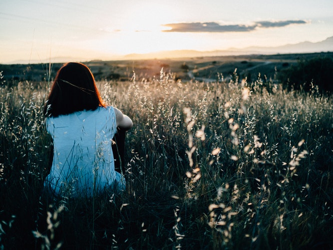 Girl sitting in field filled with wild flowers