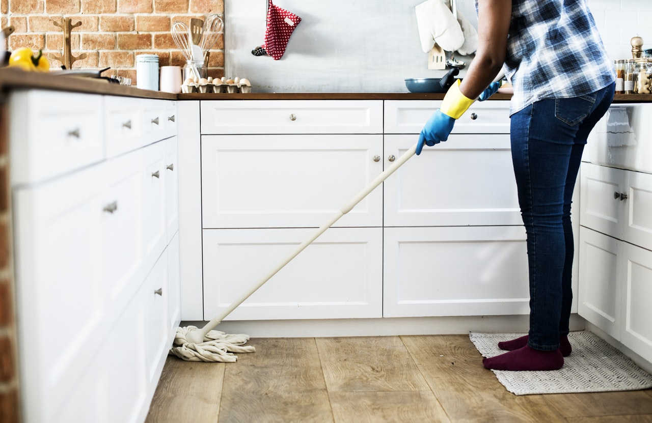 Woman mopping kitchen floor.