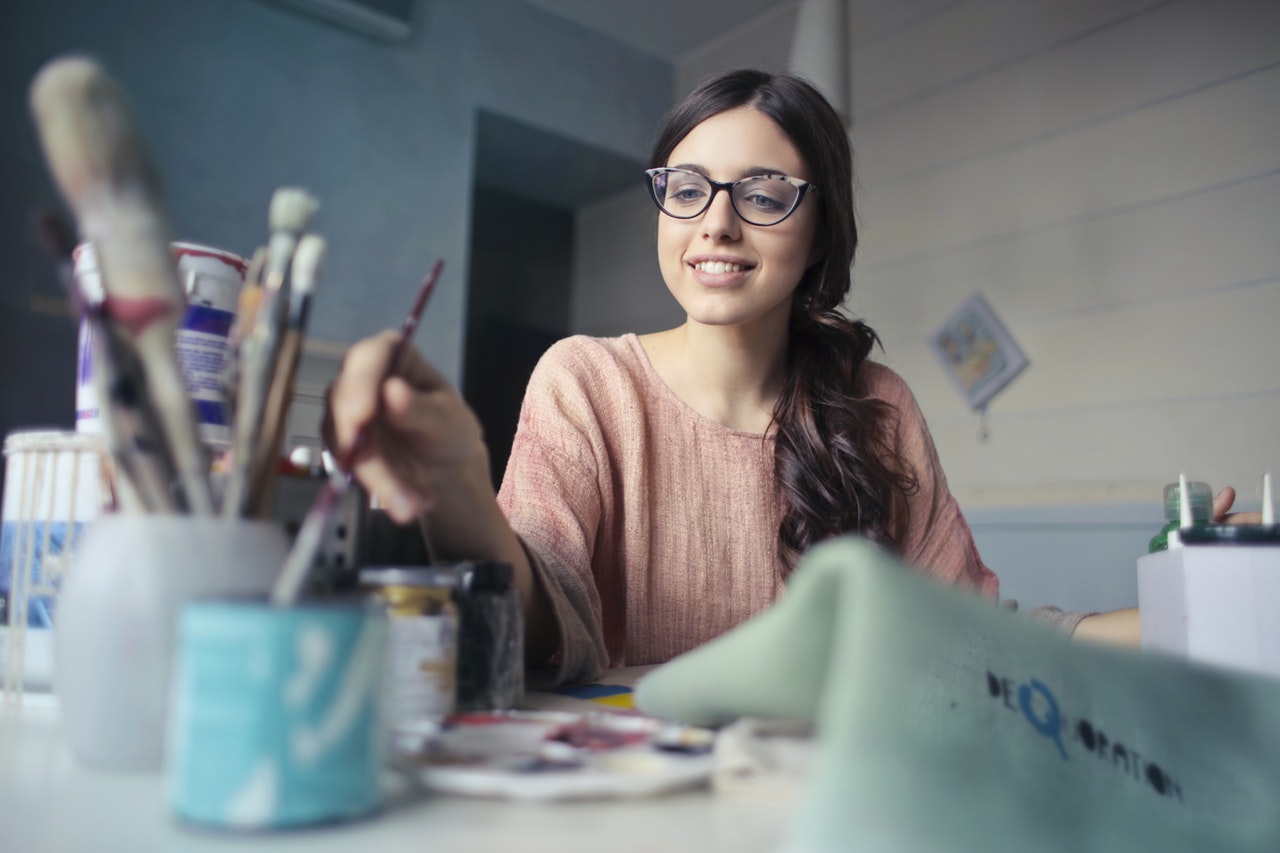 Woman sitting at desk holding paint brush