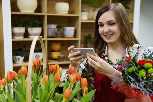 Woman taking photo of floral arrangement