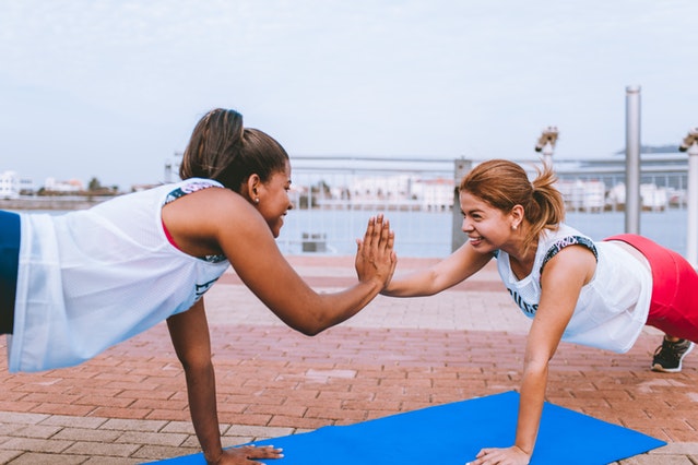 Two women doing yoga along waterfront