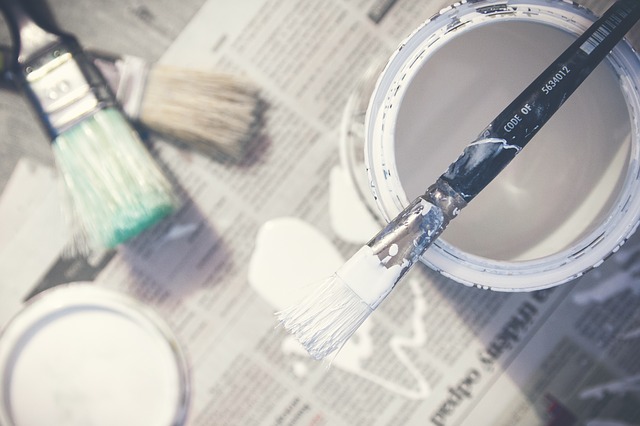 Can of white paint and paint brushes on drop cloth