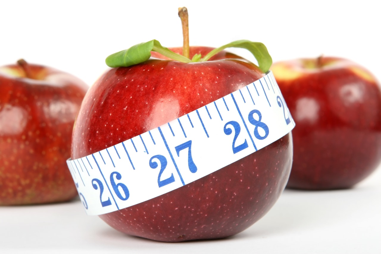 measuring tape circling red apple