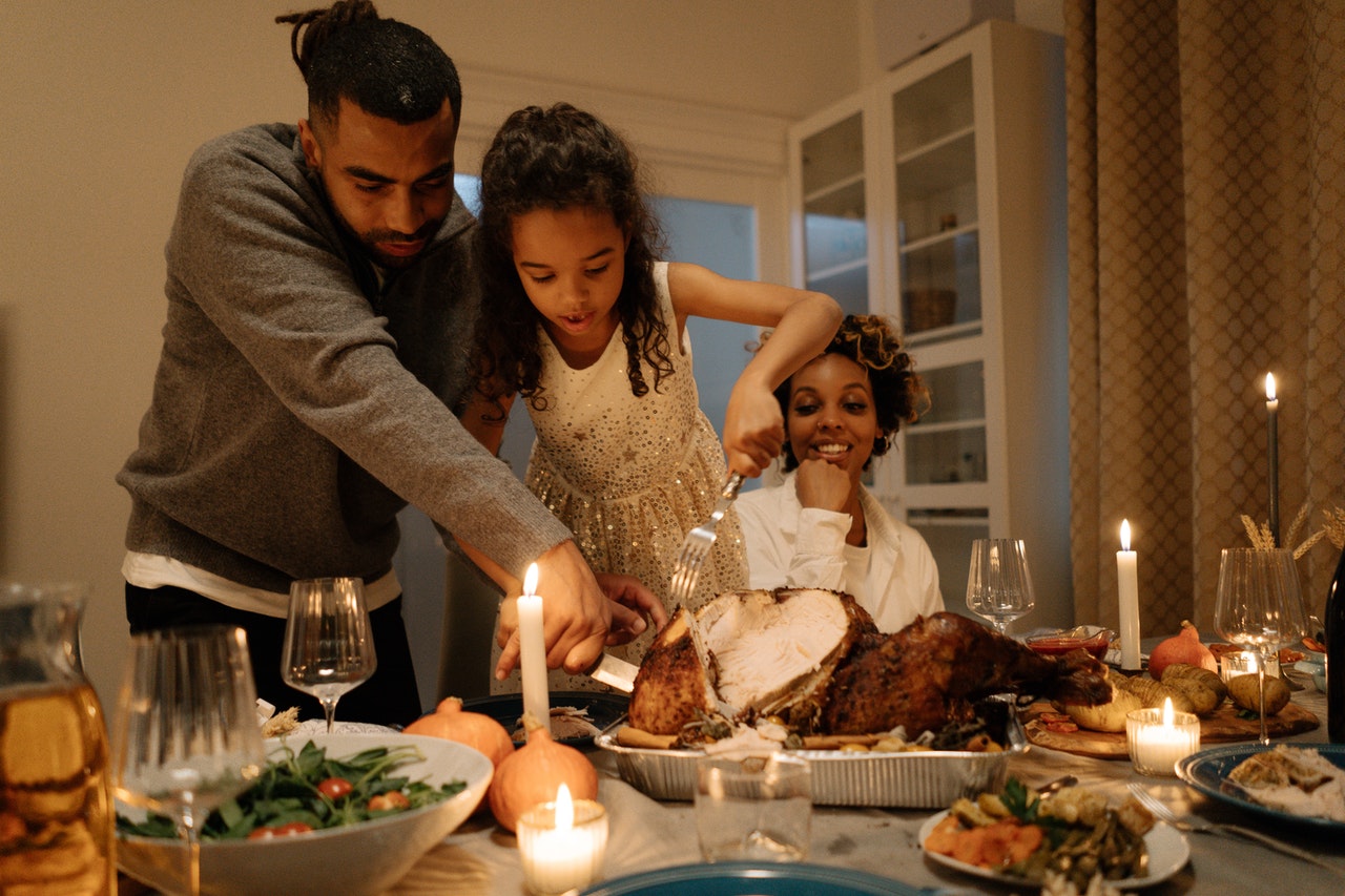 family standing around table enjoying Thanksgiving meal